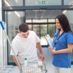 Young man with down syndrome working in a hospital as cleaner, talking to nurse, having fun. Concpet of integration people with disability into society.